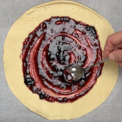 Step 3 - Unroll the pie dough on parchment paper that's placed on a baking sheet.Warm the blackberry jelly in the microwave so it becomes just liquid and allow it to cool a little. Jelly is much easier to spread when it is slightly warm. Spread like you would spread tomato sauce on a pizza bottom and leave about 1.5-2 inches of the perimeter untouched.