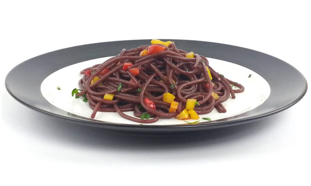 White plate with black border and drunken spaghetti with pepper confetti.