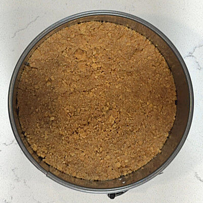Step 1 - Crush the Graham crackers until you have fine crumbs. Transfer the crumbs into a bowl, and add the melted butter and granulated sugar. Mix until you have a homogeneous mixture. Press the buttery crumbs on the bottom of the lined spring form pan and flatten it with your hands, creating the base of the cheesecake.