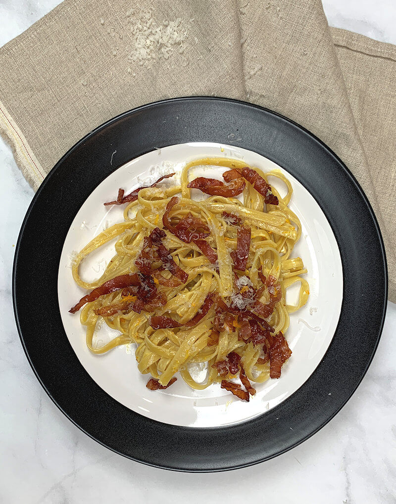 White plate with black perimeter and Tagliatelle with Prosciutto & Orange Cream