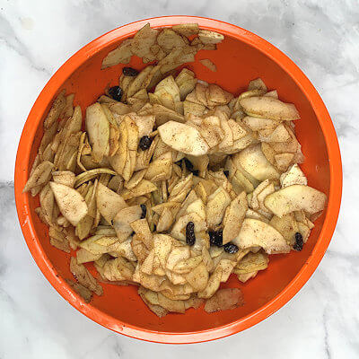 Step 2 - Make the filling by peeling the apples and slices them thin, by hand or use a mandolin. Add raisins, lemon juice, cinnamon, granulated sugar and corn starch and mix. Set aside.