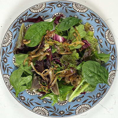 Step 1 - Heat 1 tablespoon of olive oil in a skillet and add the onion. Bake the onion until it is lightly caramelized. Allow to cool.Transfer the mixed salad green over 2 plates and divide the caramelized onion on top of the salad.