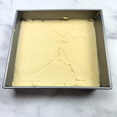 Step 2 - Transfer dough into a buttered 9x9 baking dish and press it down. Level it and smooth out the top, with you hands or the back of a spoon or an offset spatula.