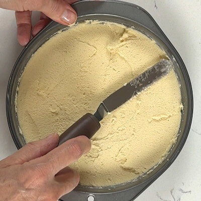 Step 4 - Transfer dough into a buttered 8' round baking dish and press it down. Level it and smooth out the top, with the back of a spoon or an offset spatula.