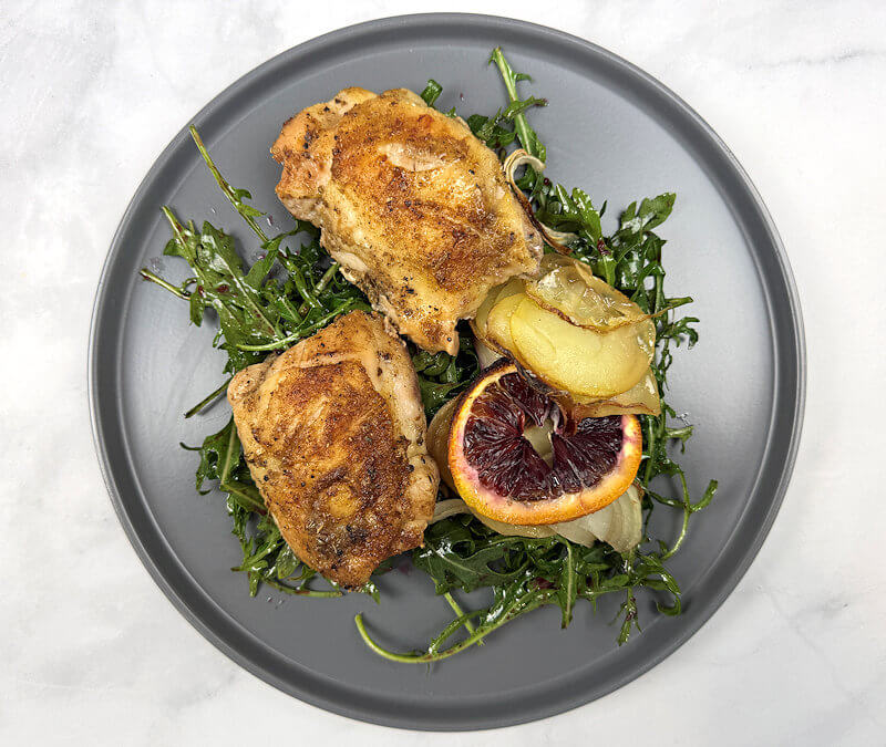 Skillet-Roasted Citrus Chicken for Two plated on a bed of arugula salad
