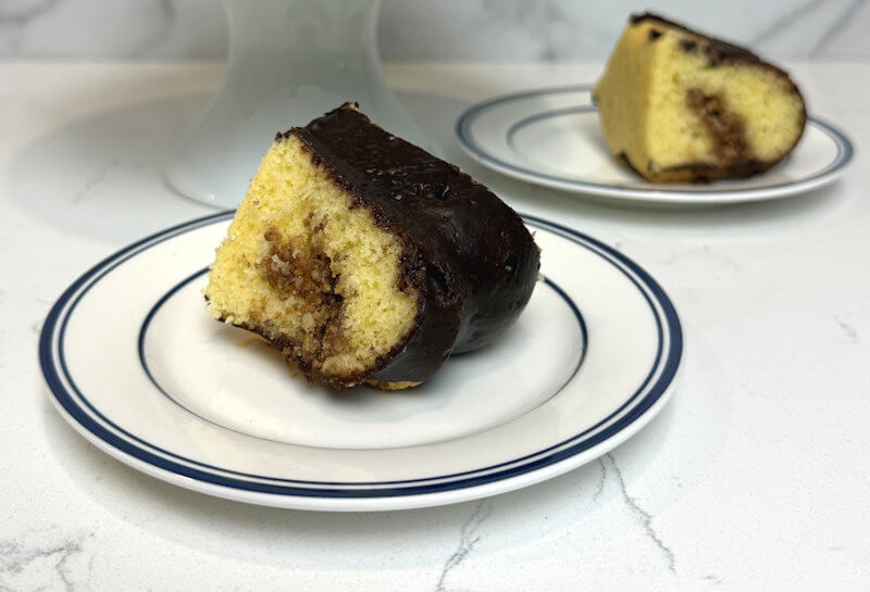 Wedge of Coffee cake with chocolate glaze on small white plate.