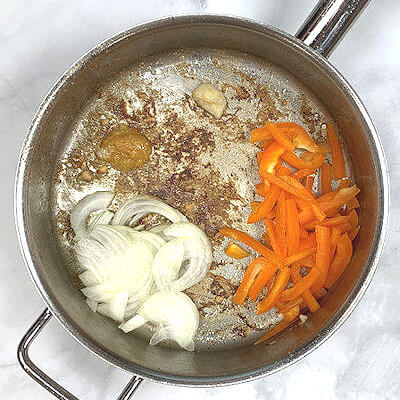 Step 2 - Add garlic, ginger, onion, bell pepper into same skillet. Saute, stirring frequently until vegetables soften, 1-2 minutes