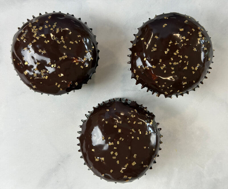 3 chocolate cupcakes with glossy ganache topping