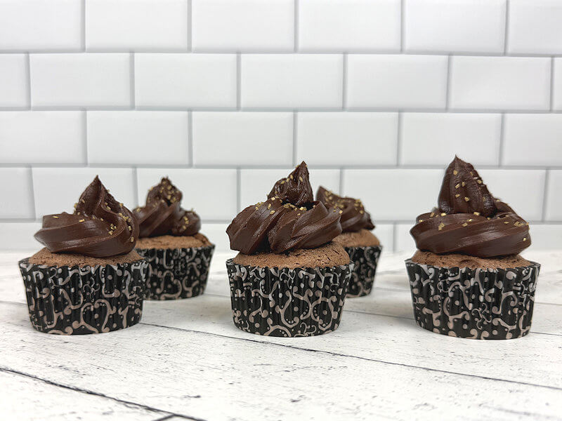 6 chocolate angel food cupcakes decorated with dark chocolate ganache and gold sugar sprinkles