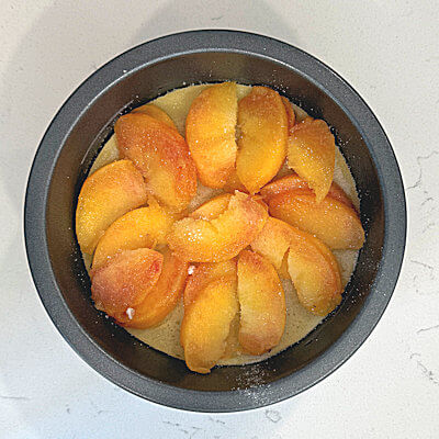 Step 3 - Remove from oven and cover with the peach slices. Place the slices in circles, and add a second layer if you have fruit left. Sprinkle with the remaining sugar.