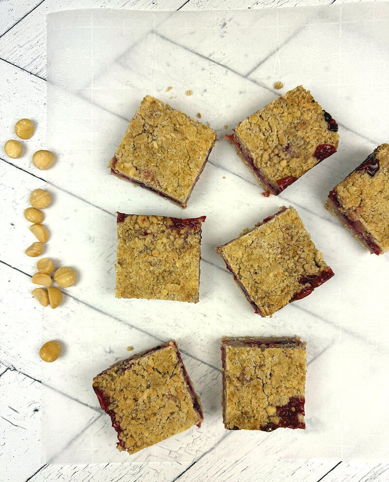 Strawberry Oat Macadami Bars spread on a sheet of parchment paper.