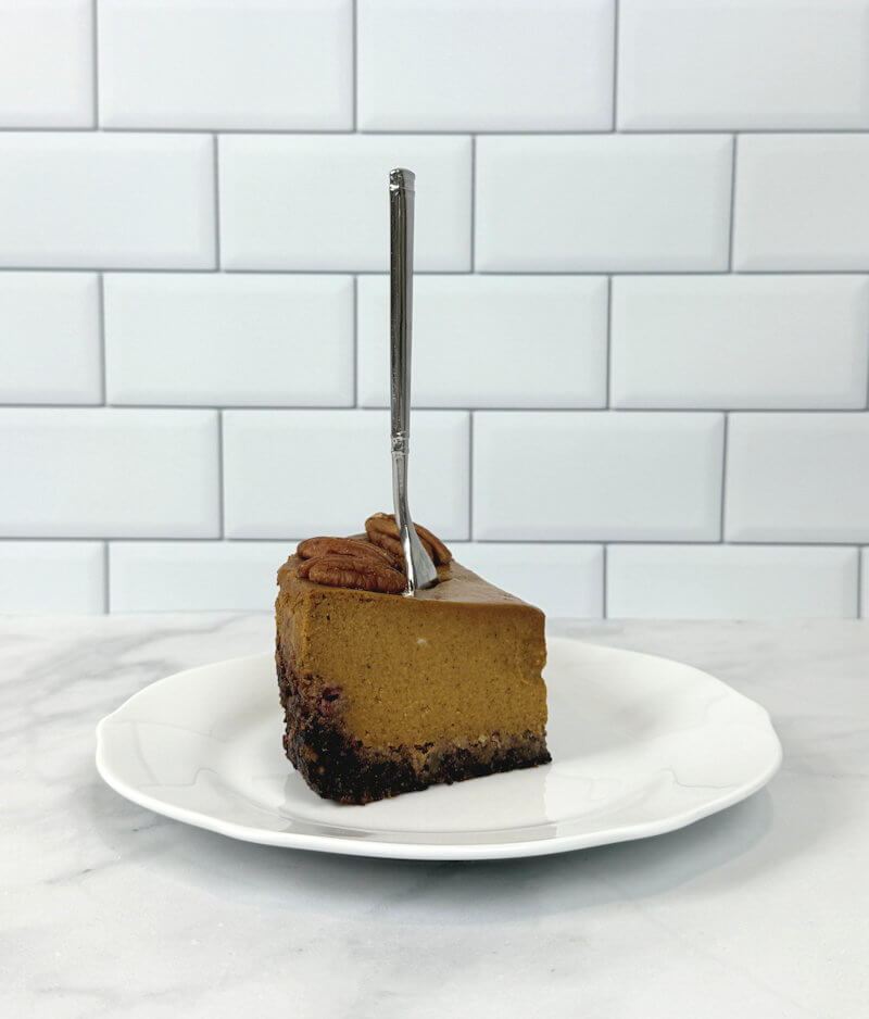 Wedge of pumpkin pie on date-pecan crust with fork