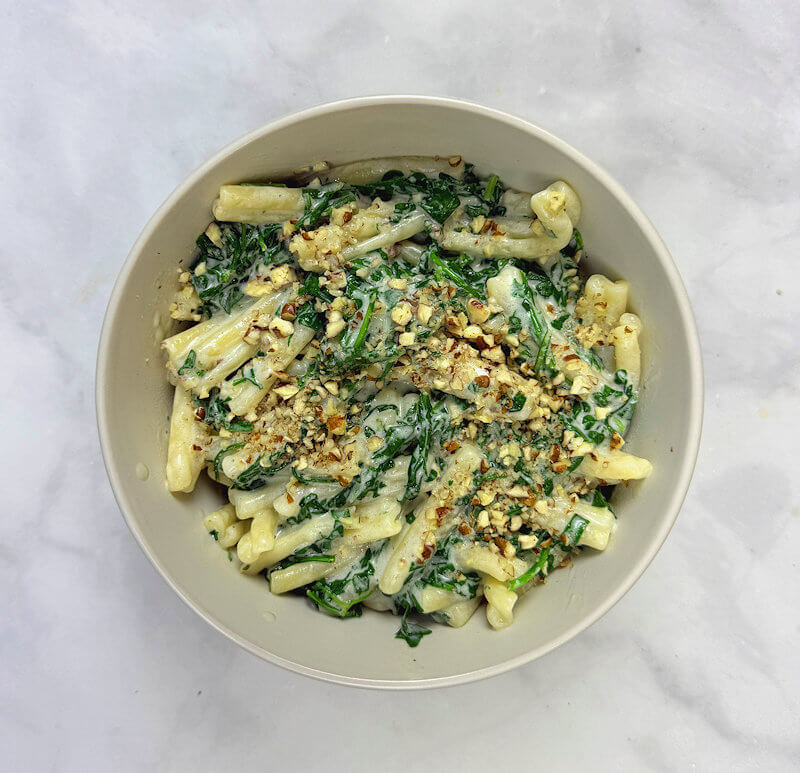 Divide the pasta over 2 plates or bowls and sprinkle with the chopped pecans.