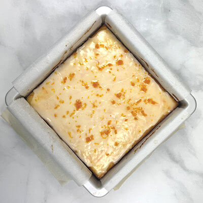 Step 6 - Bake until golden brown and the center is slightly wobbly when the pan is gently jiggled, 25-30 minutes. Cool in the pan on a wire rack to room temperature.Make glaze by mixing sugar, orange juice and pour over the cooled cake. Sprinkle with the orange zest