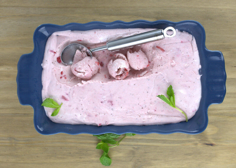 Blue bowl with strawberry ice cream and ice cream scoop making ice cream curls