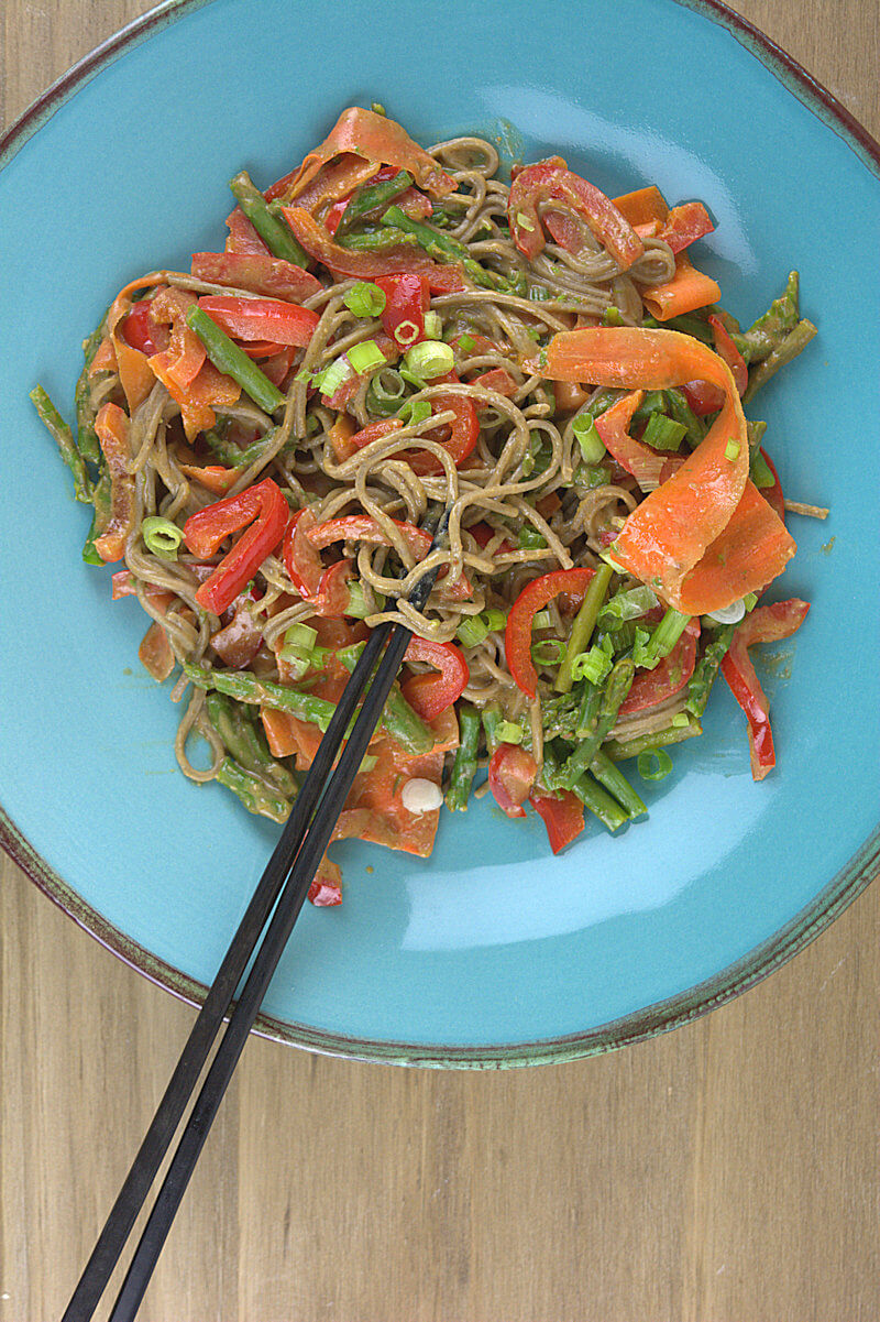 Light blue plate with Soba Noodles with Vegetables in Peanut Sauce and black chopsticks.