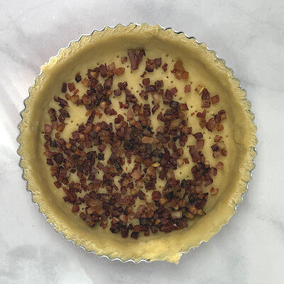 Step 5 - Transfer pancetta into the quiche form, divide evenly over the bottom.