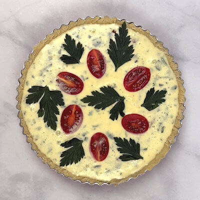 Step 7 - Divide tomato-halves over the quiche form and place a parsley sprig on top as well (optional).