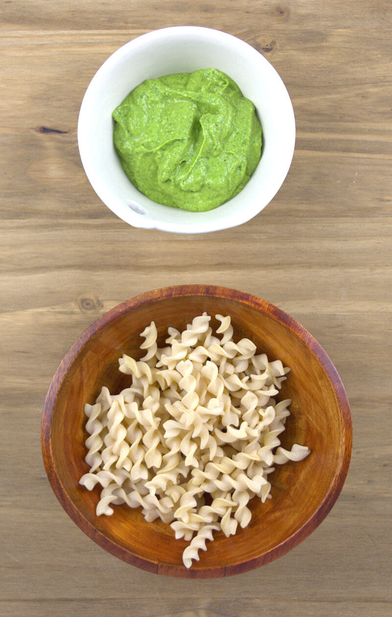 Avocado sauce and pasta in separate bowls.