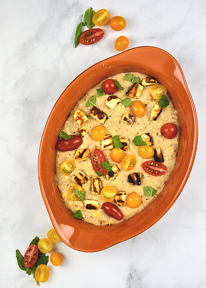 Terra cotta colored dish with creamy grits with halloumi & tomatoe