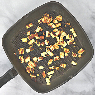 Step  1 - Grill the Halloumi cheese. Use a grilling pan and add the cubes Halloumi cheese. No need to add any oil or butter. This cheese grills beautifully and fast; don't walk away from it. You can decide whether you like the cubes brown or blackened, without burning them. For this particular dish, I have a mix of brown and blackened; I like that combination on the creamy grits.