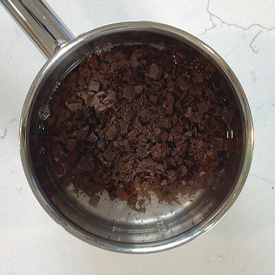 Step 3 - Heat water in a saucepan and add the chopped dark chocolate. Cook until melted.