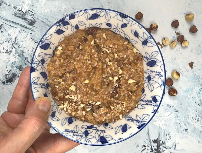 Hand holding bowl of apple cherry steel-cut oatmeal