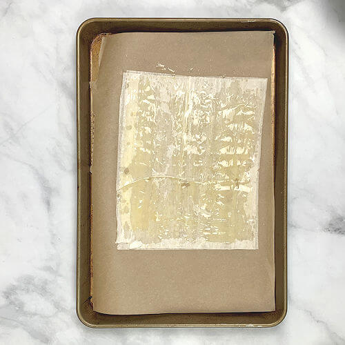 Baking sheet with 2 sheets of phyllo dough, each brushed with butter.