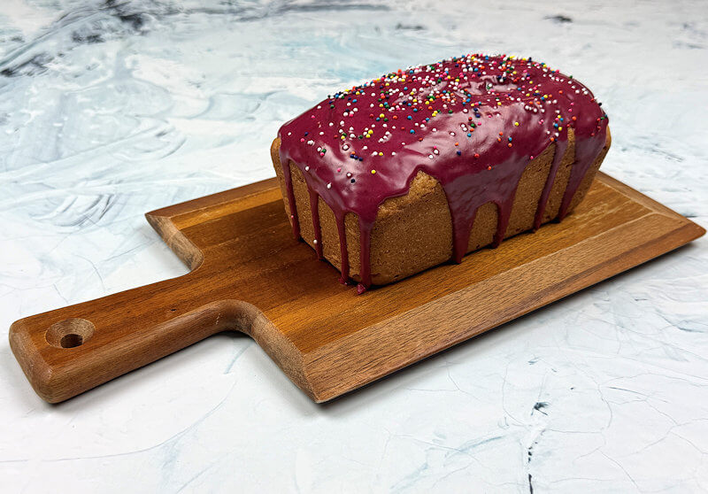 Uncut Blueberry-Glazed Lemon Yogurt cake on wooden plank