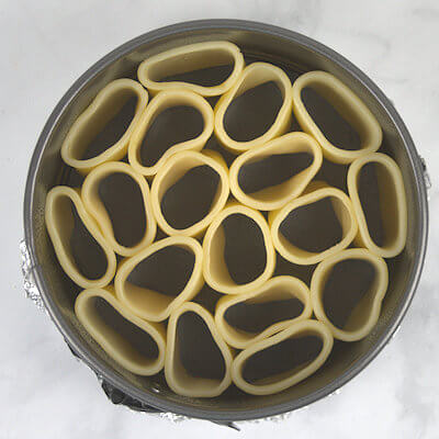 Step 4 - Wrap the bottom of the spring form pan with aluminum foil, just in case some of the sauce leaks out of the pie dish. Grease the inside of the spring form with olive oil and place the cooked pasta in the form, as tight as possible.