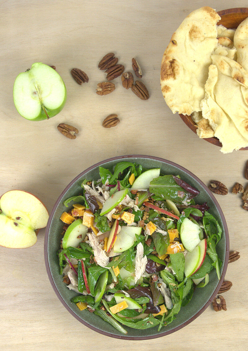 Green bowl with apple, cheddar & turkey salad as well as naan and pecans
