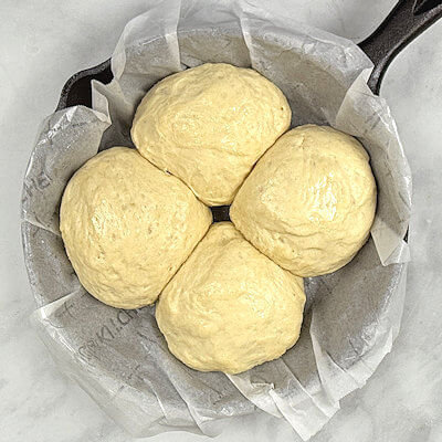 Step 3 - Cut dough into 4 equal parts, roll into balls. Place dough balls in a oven-safe dish or cast-iron skillet, cover and allow to rise again.