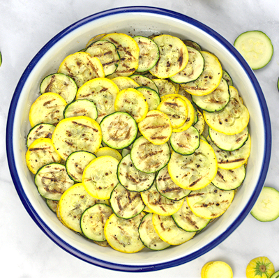 Step 4 - Place grilled zucchini and squash slices in a pie dish in overlapping circles, two circles in total. Alternate green and yellow.