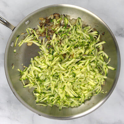 Step 2 - Heat olive oil in a skillet and add the onion, cook until brown and caramelized, about 5 minutes. Add the zucchini and cook a few more minutes. Add salt and pepper.