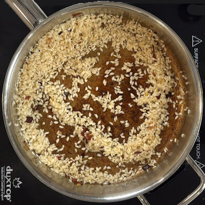 Step 2 - Heat the remaining butter in the same pan, add the rice and stir until every grain is coated with the butter. 