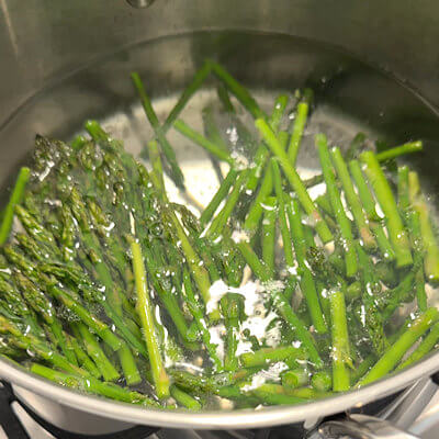 Step 3 - Cook the asparagus in water with salt for about 3-5 minutes, add the frozen peas the last 2 minutes. Keep some of the asparagus tops as well as some peas aside (these will become the decorations of the tart). Drain the vegetables well; the drier the better. Too much moisture may result in the filling oozing out of the tart at the moment of cutting. Shred the Gruyère cheese.