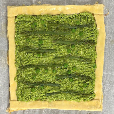 Step 5 - Transfer the vegetable-cheese mixture onto the tart and spread towards the edges, not over the edges. Decorate the tart with the reserved asparagus tops and peas and slide the tart into the oven.