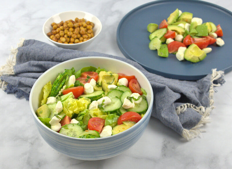 Plate with salad, bowl with salad and roasted chickpeas on the side.