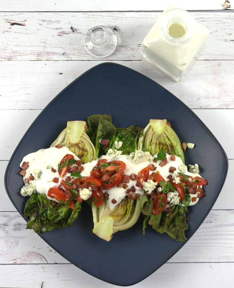Overhead image of Grilled Little Gem Lettuce with jar of blue cheese dressing