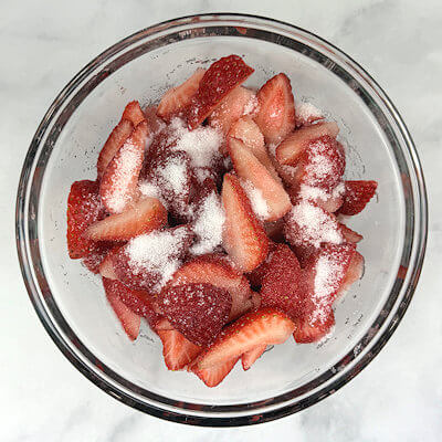 Step 2 - Was, trim and hull strawberries and cut them in smaller pieces. We're making a 6-inch pie, so strawberry halves may be too big and leave too many holes. Add sugar and set aside to macerate for at least 30 minutes.