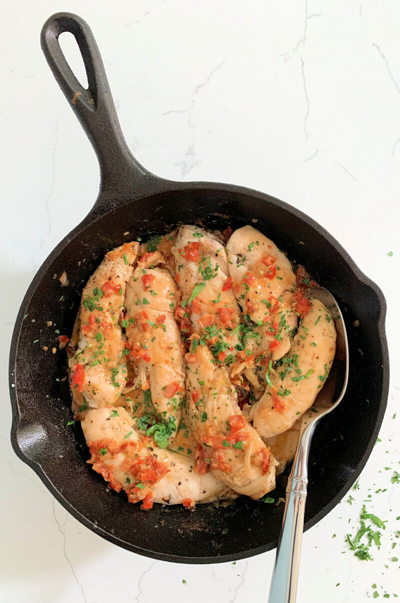 Chicken with Sundried Tomatoes in a cast-iron skillet - with a spoon.