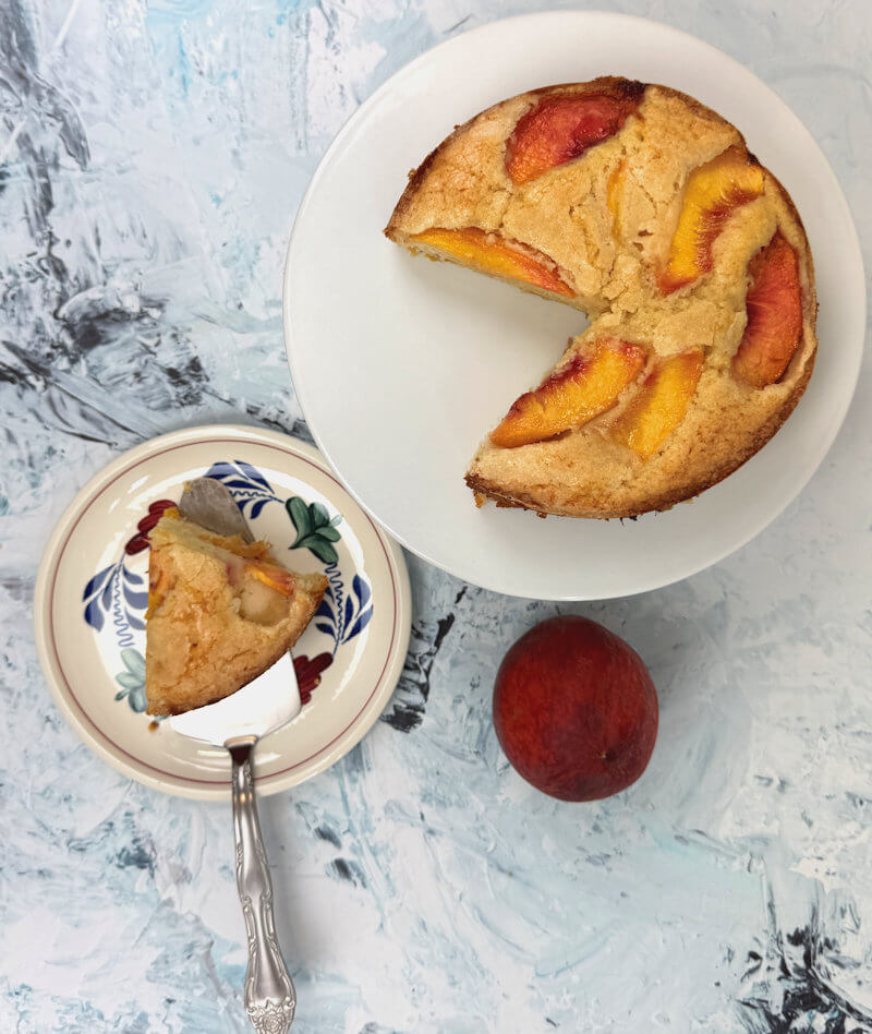 Cut peach cake on cake stand and plate with one wedge