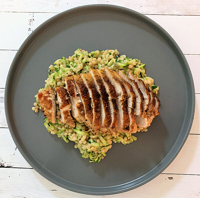 A turkey breast fillet served on a bet of Couscous with Zucchini & Herbs