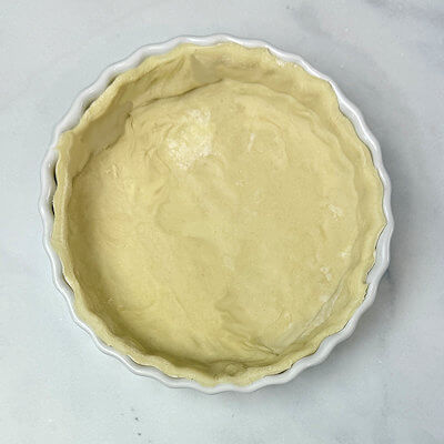Step 1 - Prepare the pie dish by brushing it with melted butter. Cut a circle out of a sheet of puff pastry, just a little bit larger than the diameter of the pie dish, so the dough also covers the sides. Transfer the dough into the pie dish and lightly press the dough against the bottom and sides.