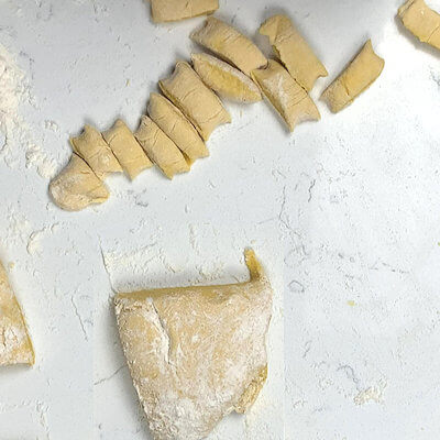 Step 5 - Transfer the gnocchi 'dough' back onto your floured surface, cut the ball in 4 parts and roll each out into a log or tube. Cut the gnocchi from that log.