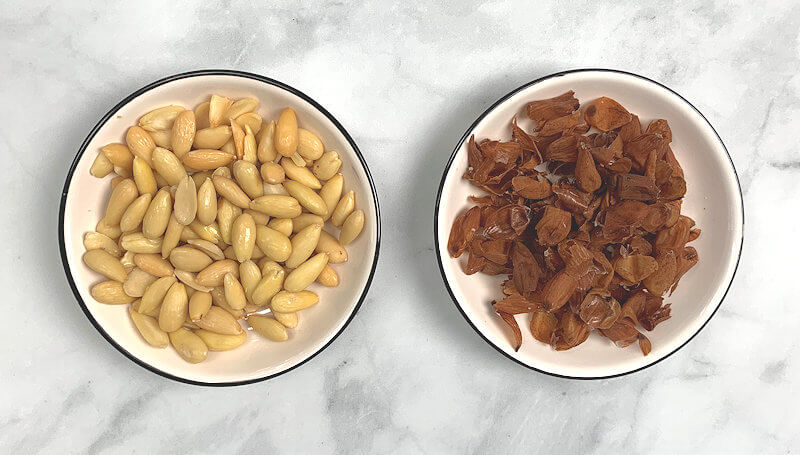 Dish with peeled almonds and another with almond skin.