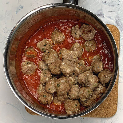 Step 6 - Heat the marinara sauce (your own creation or store-bought) and add finely chopped parsley and basil as well as the meatballs.