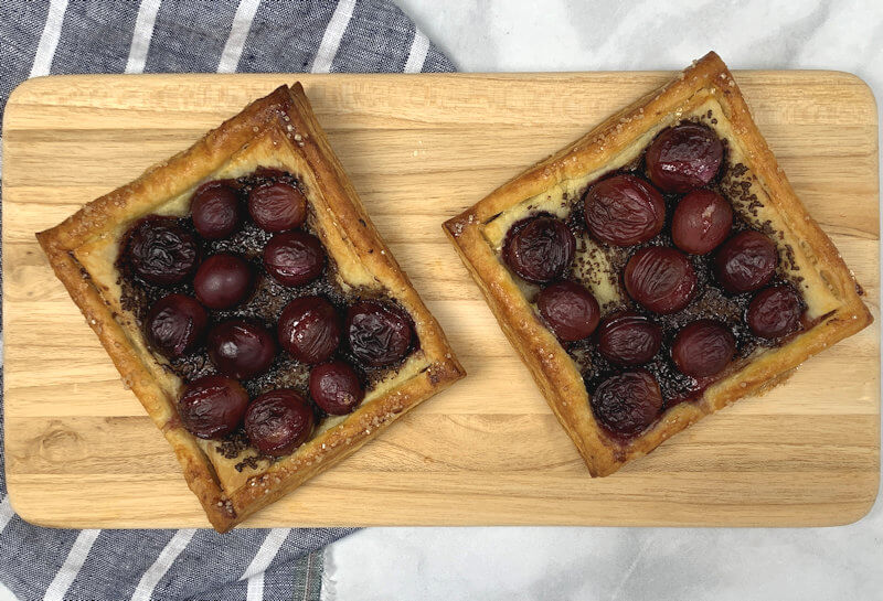Two Chocolate Grape Tarts on wooden plank