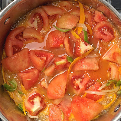 Step 2 - Heat olive oil in a pan and add the onion, citrus skins and tomato quarters. Allow to cook for a few minutes and then add the orange, lime and lemon juice. Cover the pan and simmer for about 20 minutes.