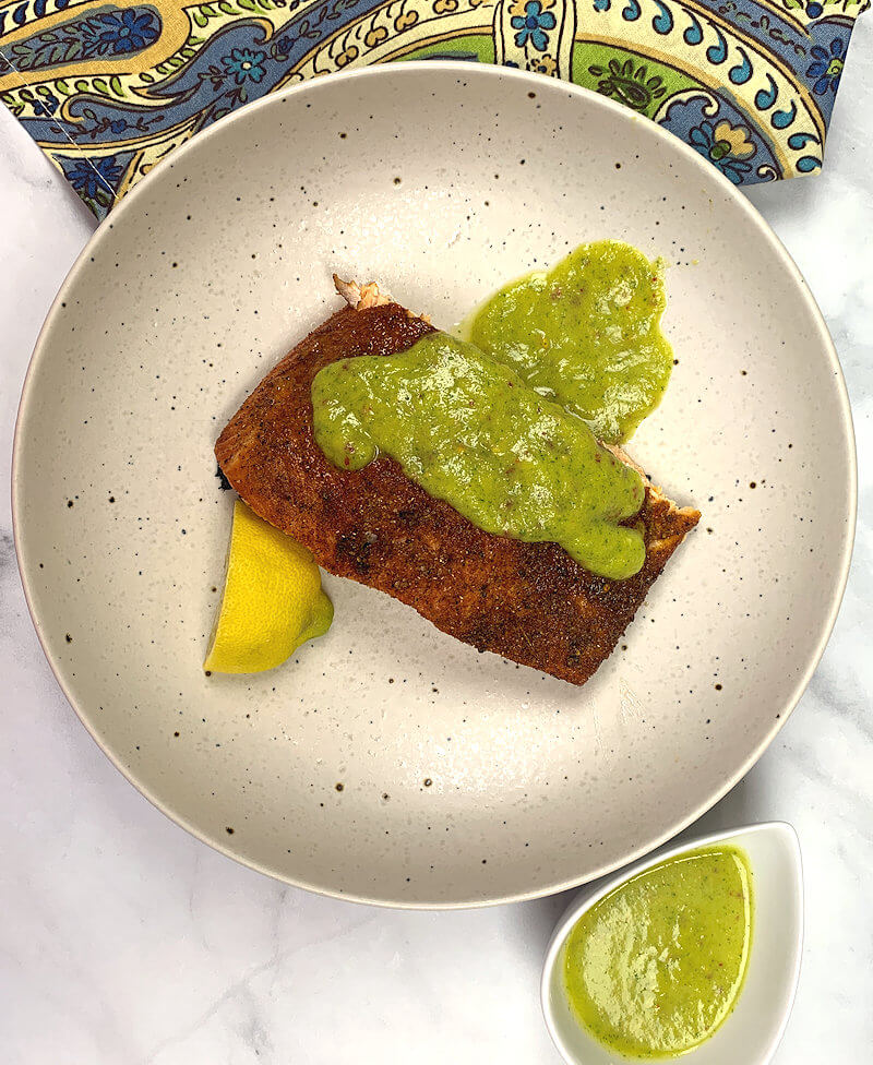 Grilled salmon served in bowl with pineapple sauce dressed over it.